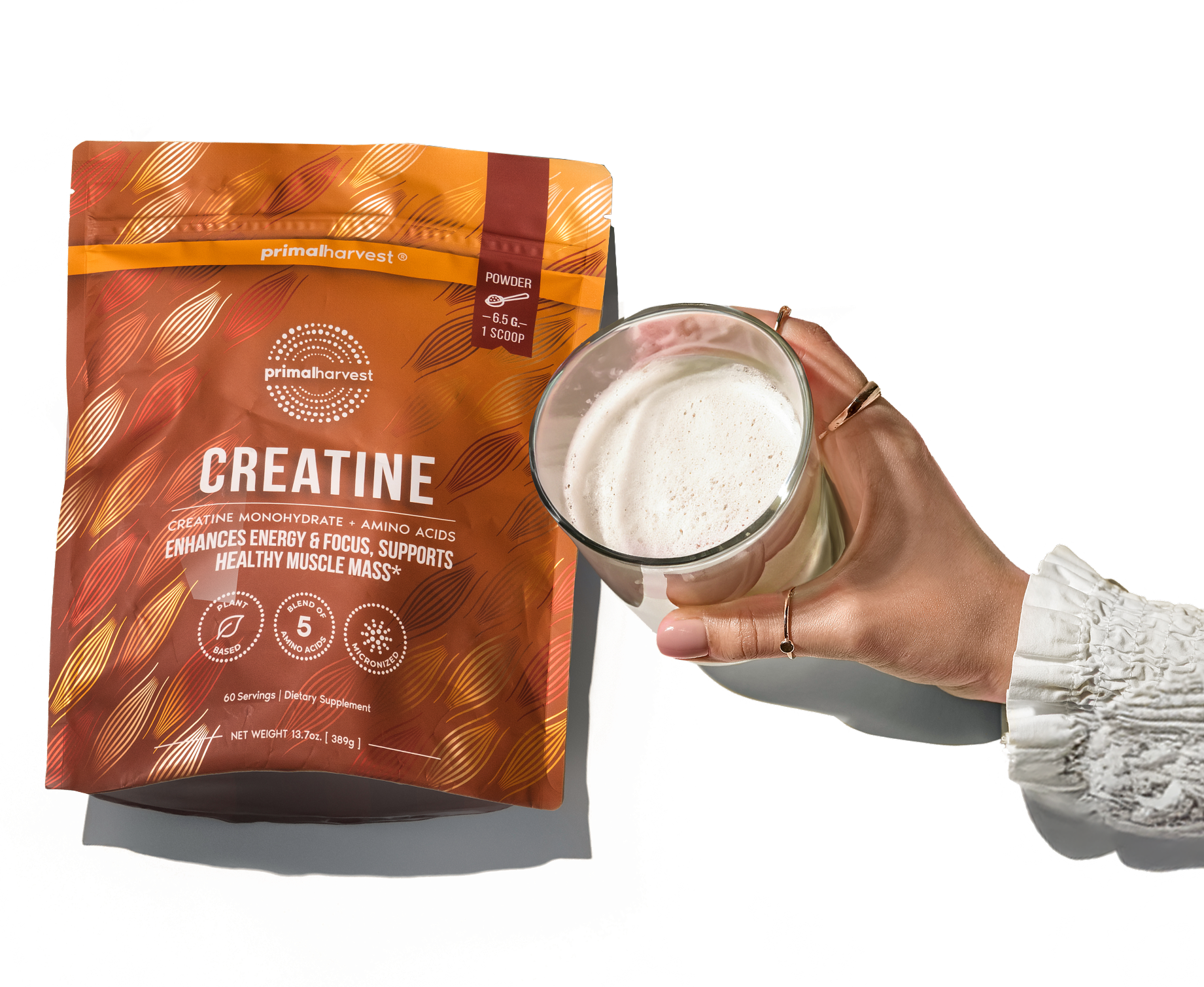 Hand holding a glass next to a creatine supplement package.