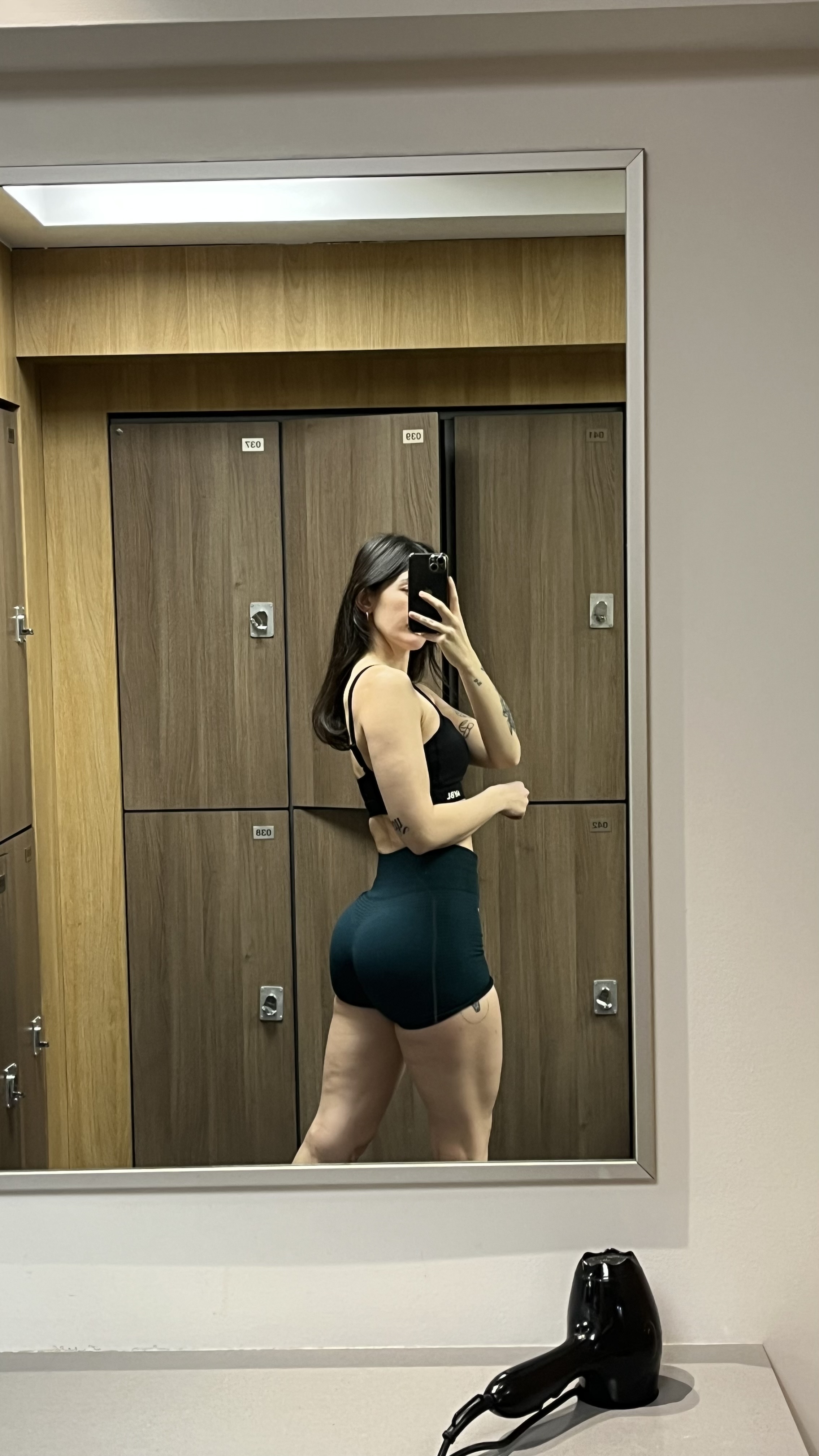 Person taking a mirror selfie in a locker room.