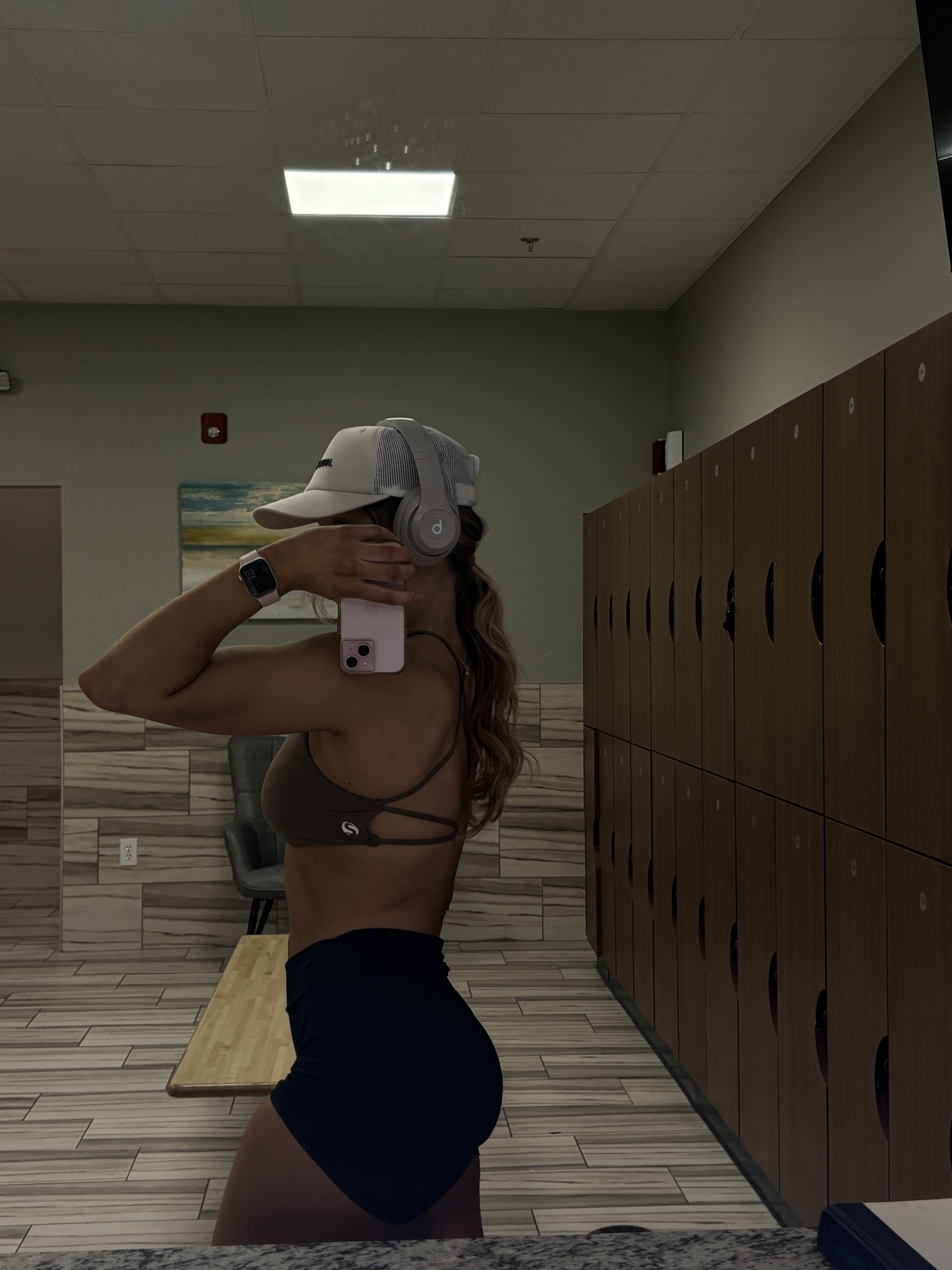 Person taking a mirror selfie in a gym locker room.