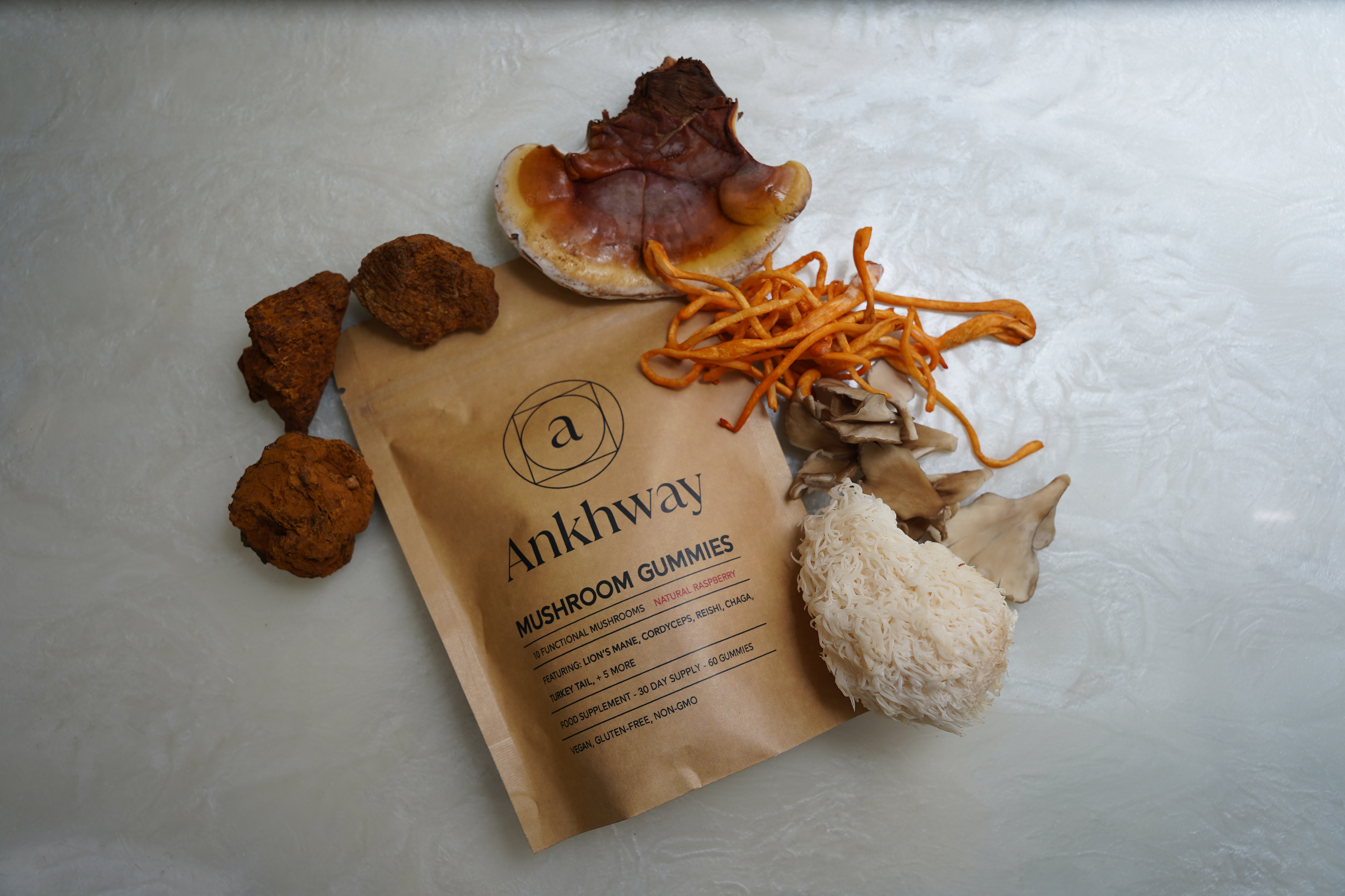 Packet of Ankhway mushroom gummies surrounded by various mushrooms on a light surface.
