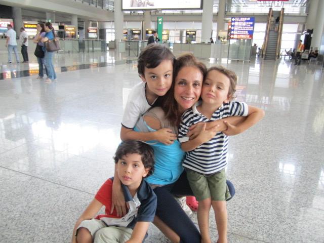 A woman hugging three children in an airport terminal.