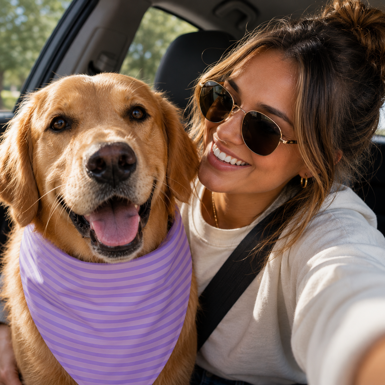 A smiling woman in sunglasses takes a selfie with her golden retriever in a car.