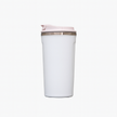 White travel mug with a light pink lid on a plain background.