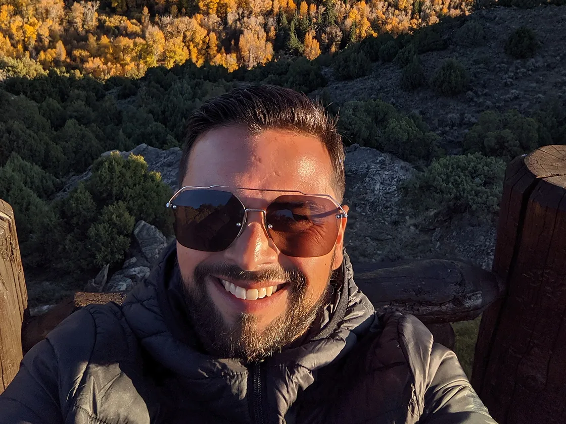 Person taking a selfie with autumn forest background.