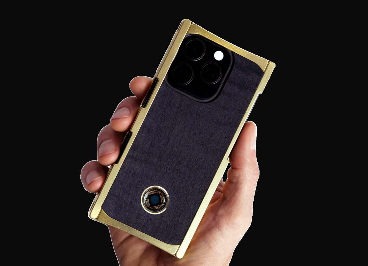 Hand holding a smartphone with a black and gold case, featuring multiple camera lenses.