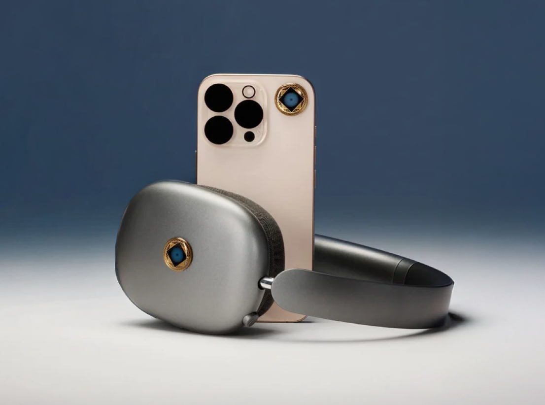 A pair of grey over-ear headphones and a gold smartphone with matching decorative gold and blue emblems.