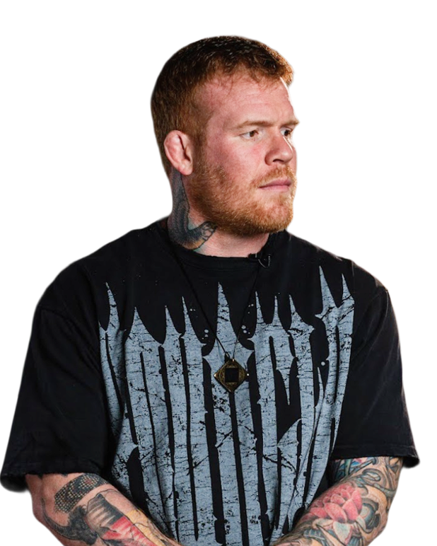 Person with tattoos wearing a black graphic t-shirt and looking sideways.