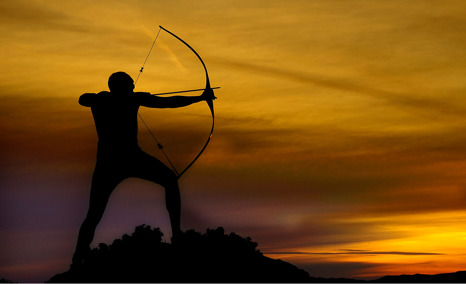 Silhouette of an archer aiming a bow against a sunset sky.