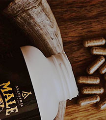 Open supplement bottle with capsules on a wooden surface.