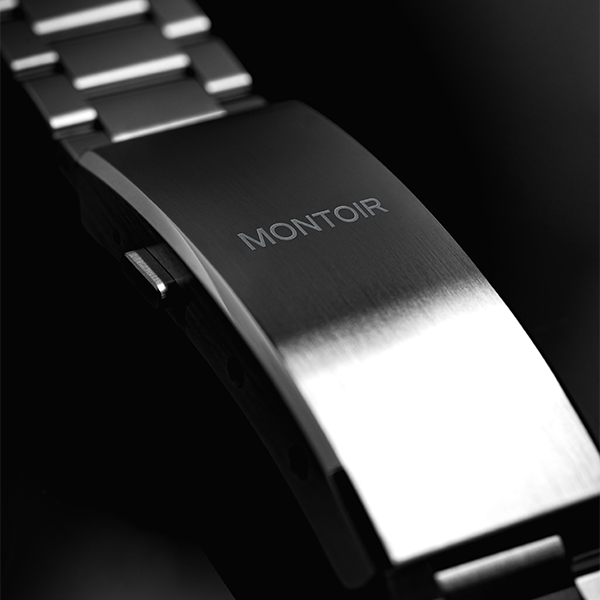 Close-up of a metallic watch clasp with 'MONTOIR' engraved.