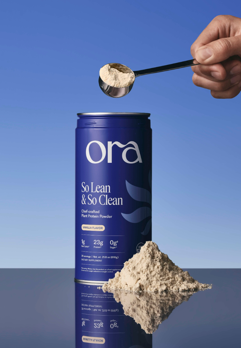 A can of Ora protein powder with a hand holding a scoop of powder above it.
