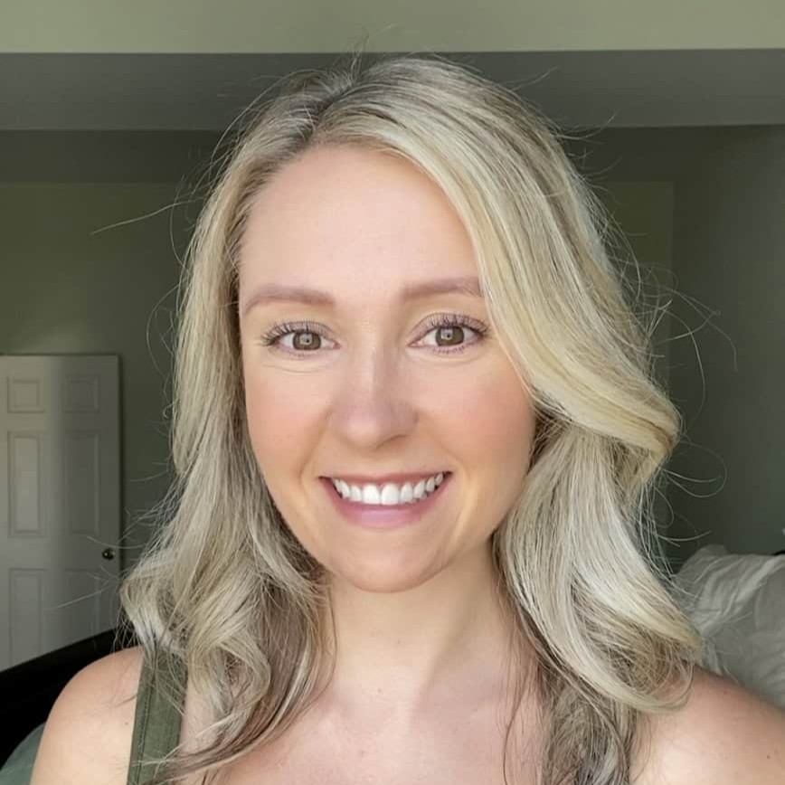 Person with long blonde hair smiling indoors.