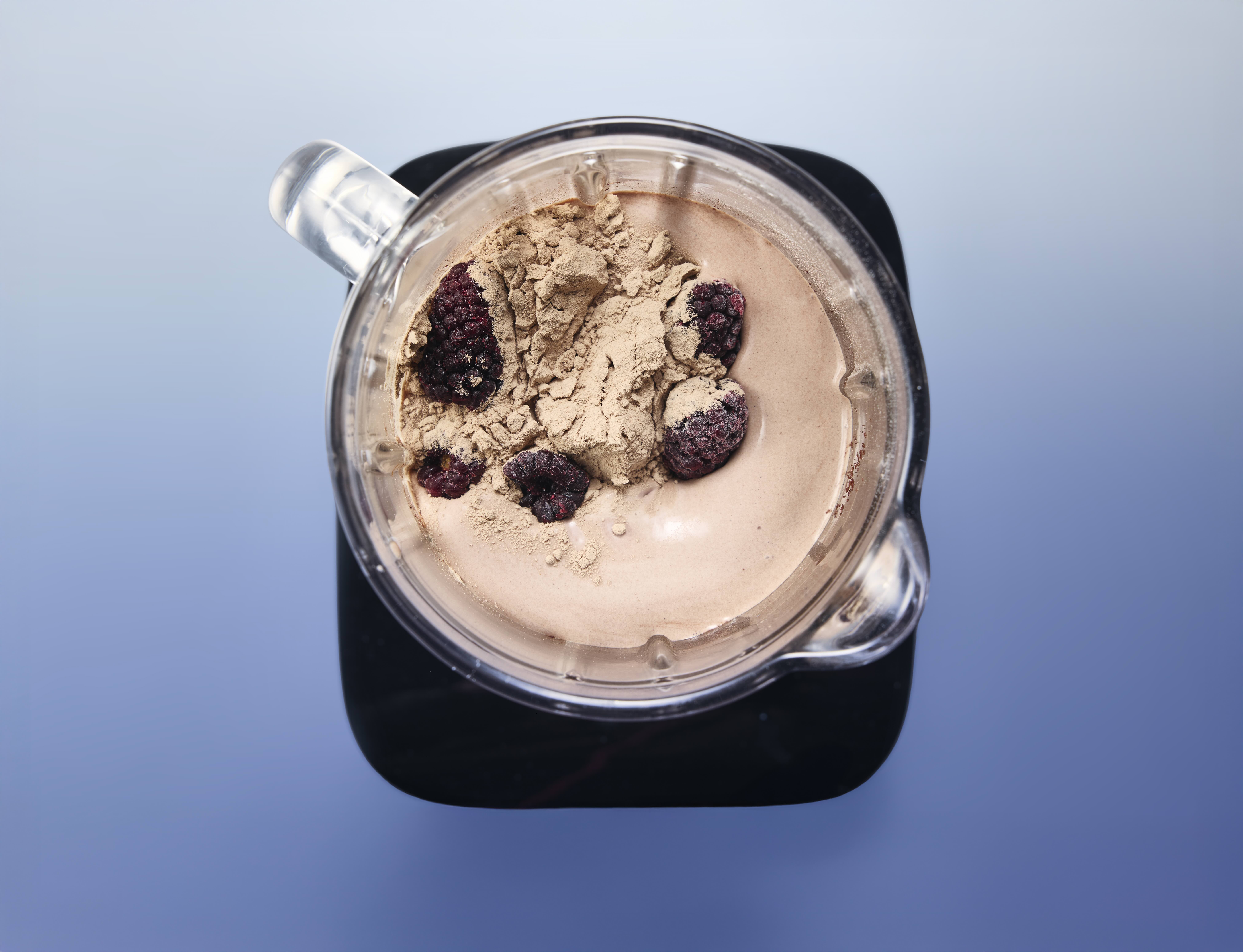 Top view of smoothie with berries and powder in blender.