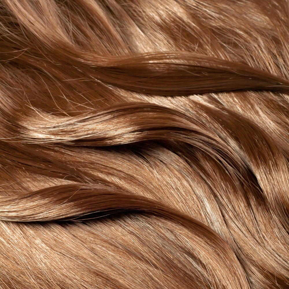 A close-up shot of shiny, wavy light brown hair.