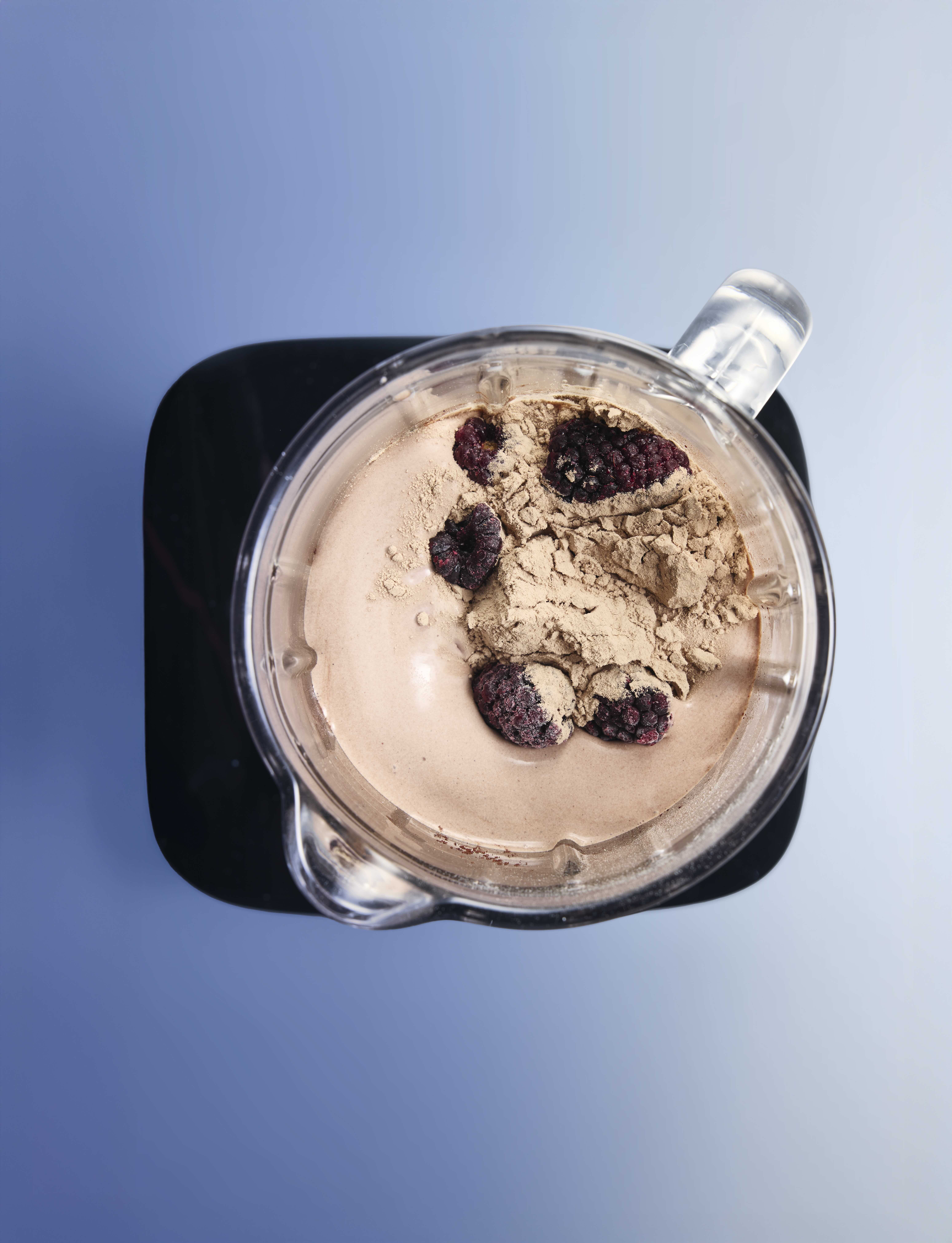 Top view of a blender with chocolate mixture and blackberries.