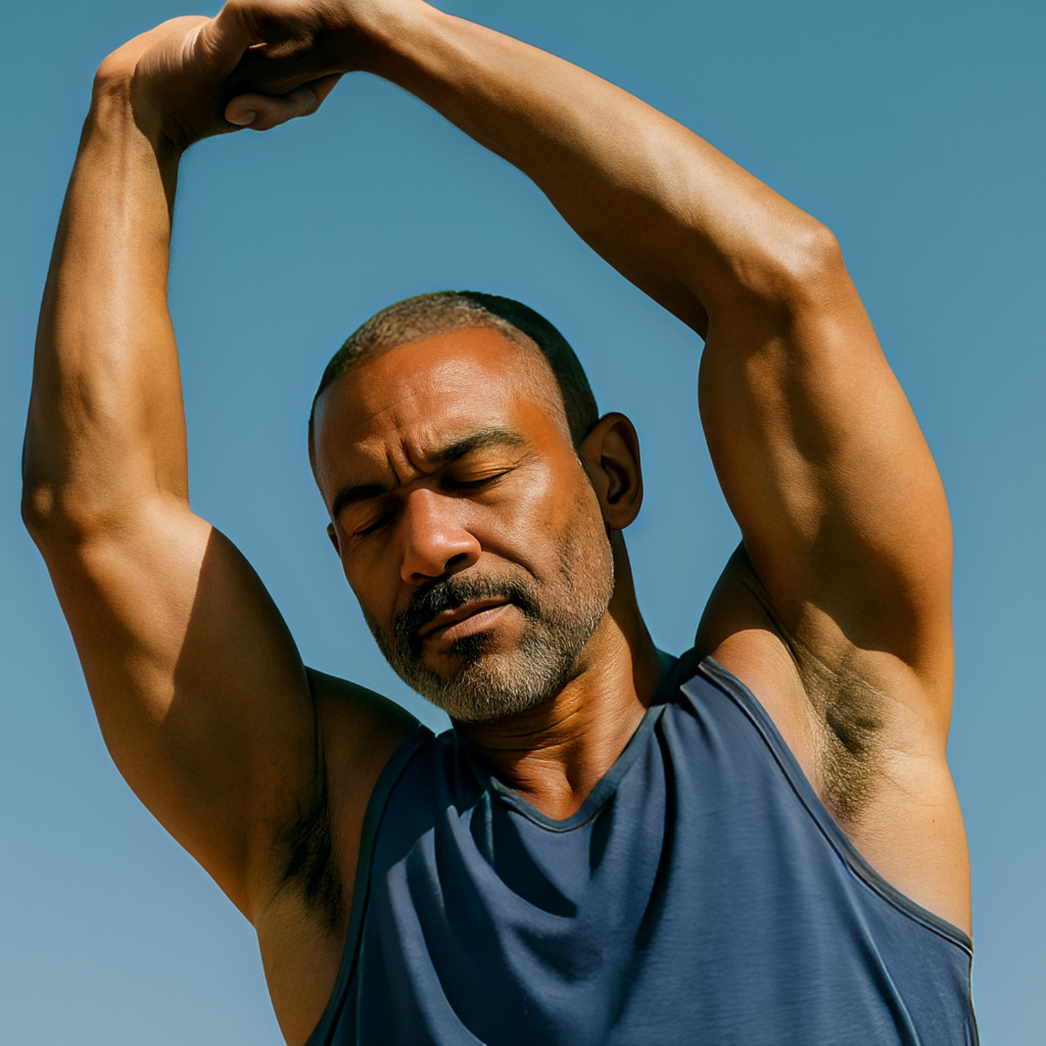 Man in blue tank top stretching under clear blue sky.