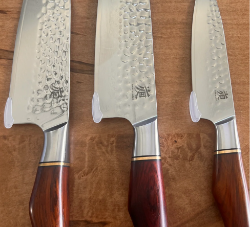 Knife and raw meat on cutting board with rosemary and salt.