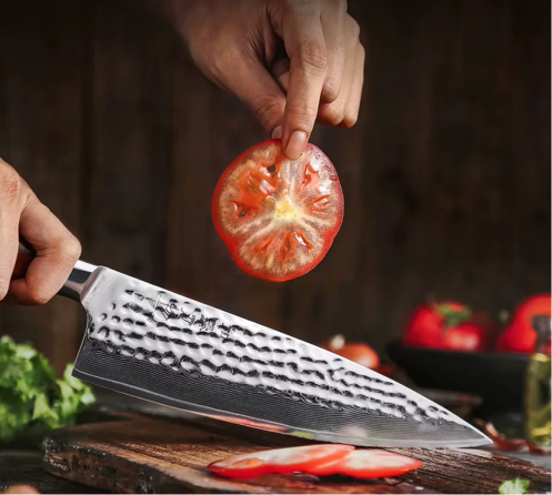 Knife and raw meat on cutting board with rosemary and salt.
