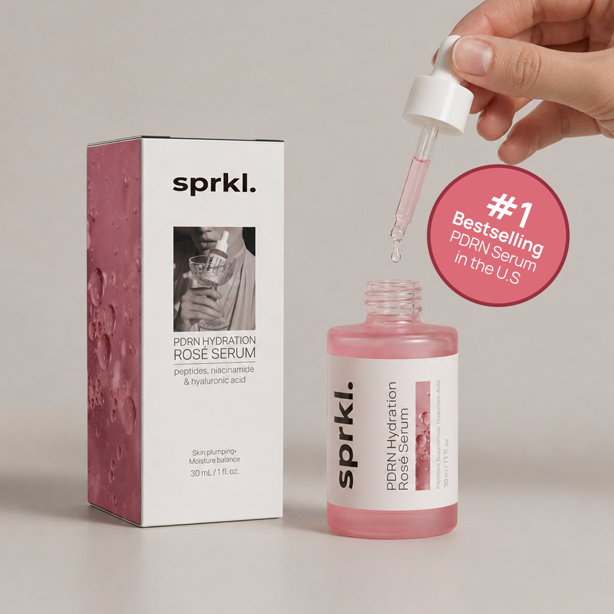 A hand holds a dropper over a bottle of sprkl. PDRN Hydration Rosé Serum, next to its box.