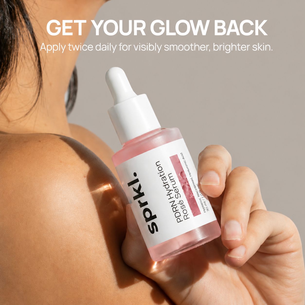 A person's hand holds a bottle of sprkl. PDRN Hydration Rose Serum against their shoulder.