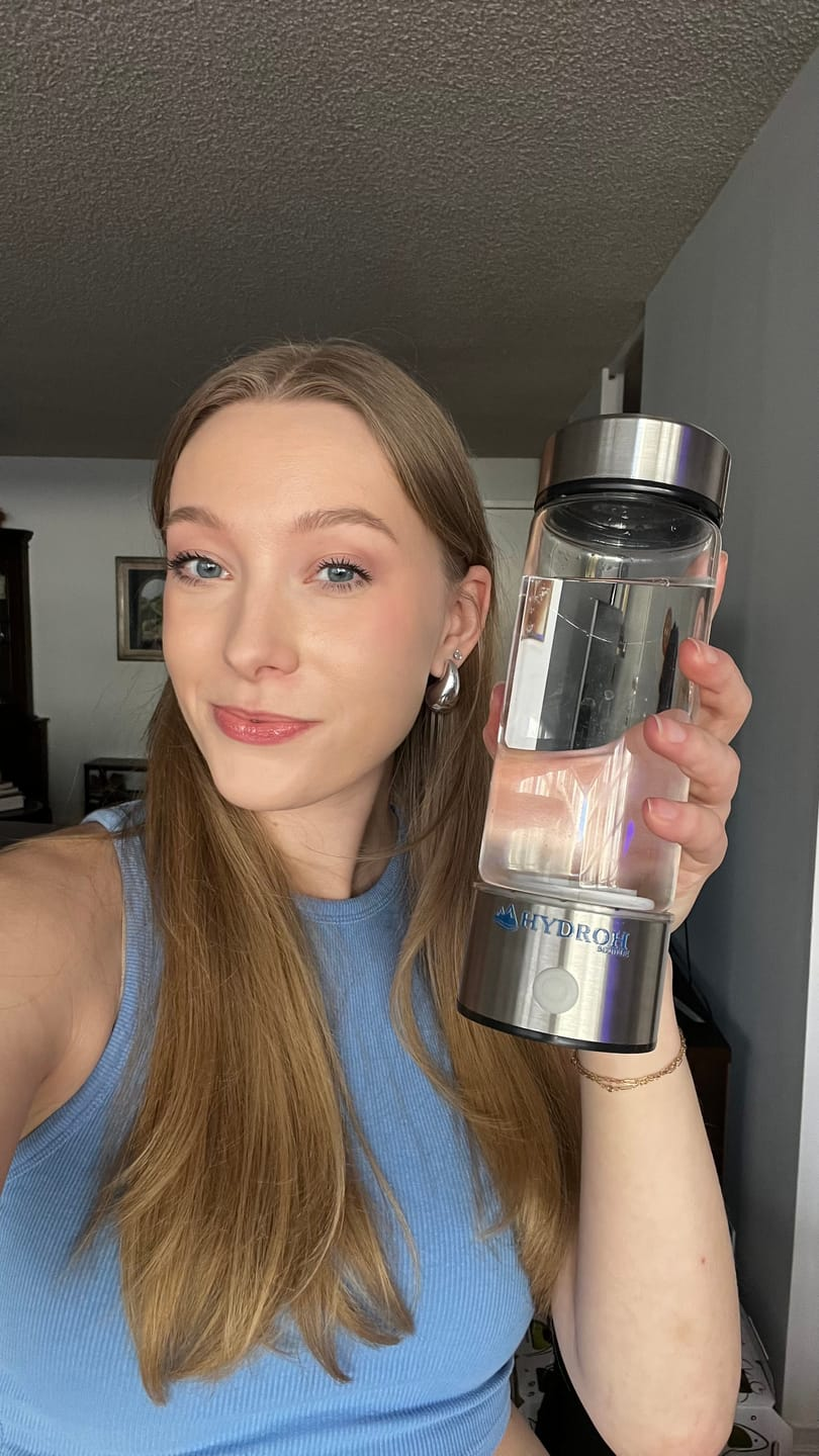 Person holding a clear water bottle with a metal lid.