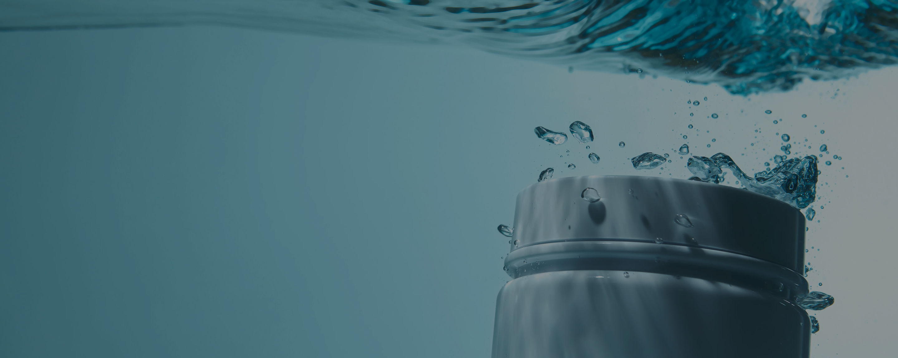 The top of a white container submerged in blue water, with bubbles rising to the surface.