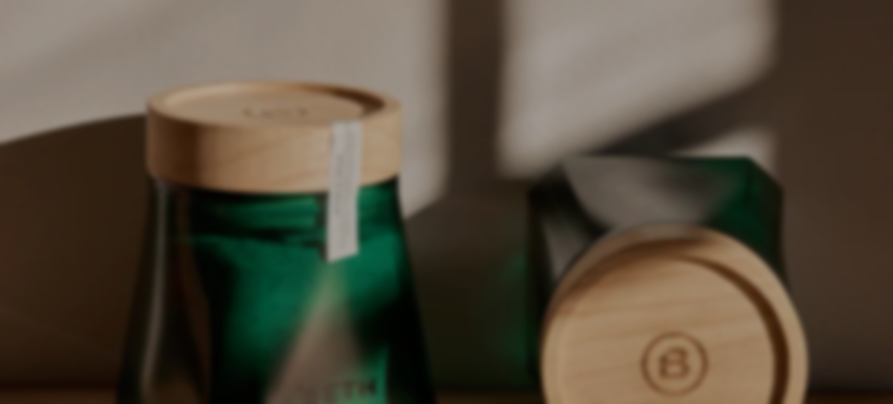 A blurry, artistic close-up of two green containers with light wood lids in a softly lit room.