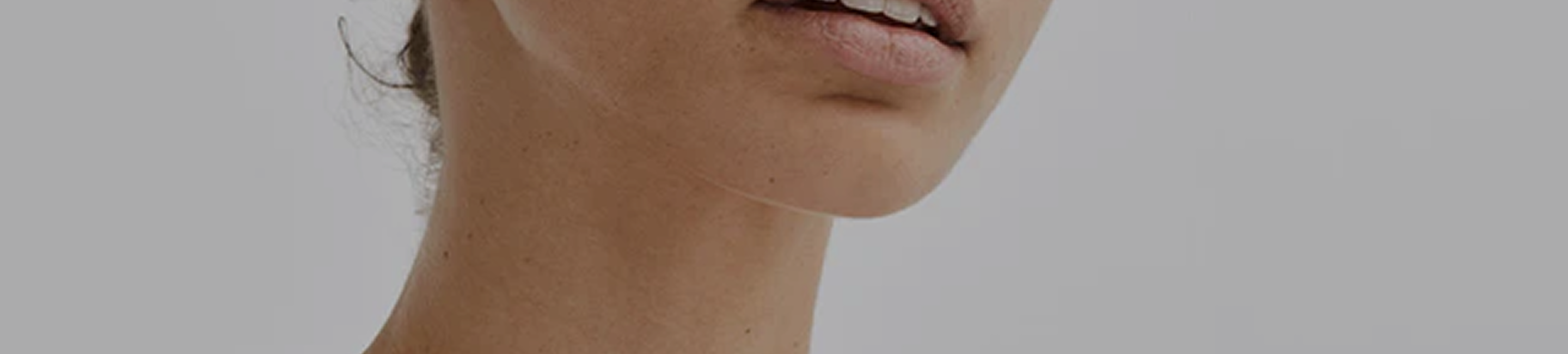 A close-up shot of the lower half of a woman's face, showing her mouth, chin, and neck.