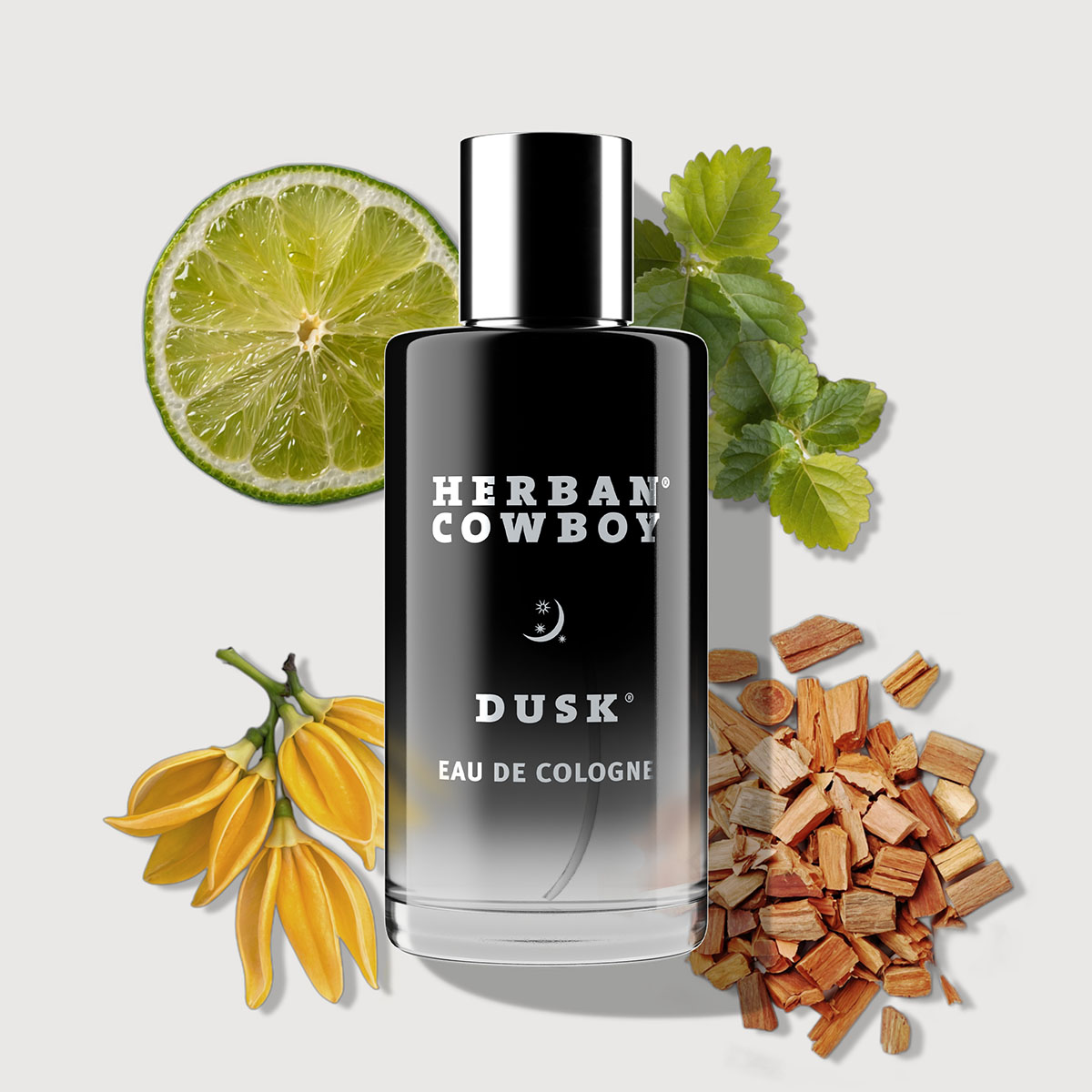 Cologne bottle with lime, yellow flowers, green leaves, and wood chips.