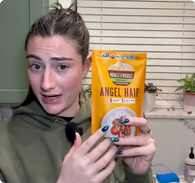 Person holding a bag of Miracle Noodle Angel Hair in a kitchen.