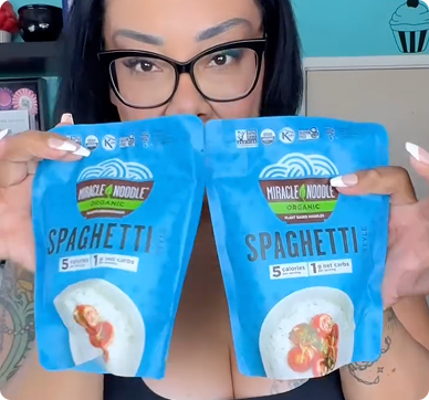 Person holding two packets of Miracle Noodle organic spaghetti.