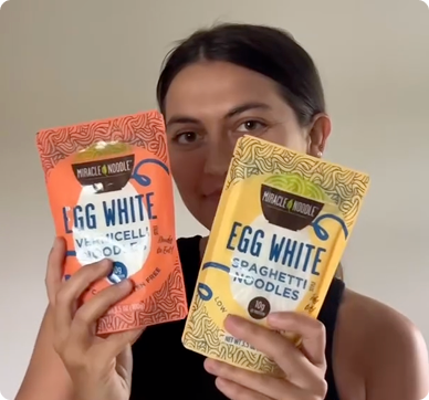 Person holding two packets of egg white noodles.