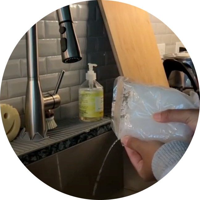 Hands holding a plastic bag with water leaking into a sink.