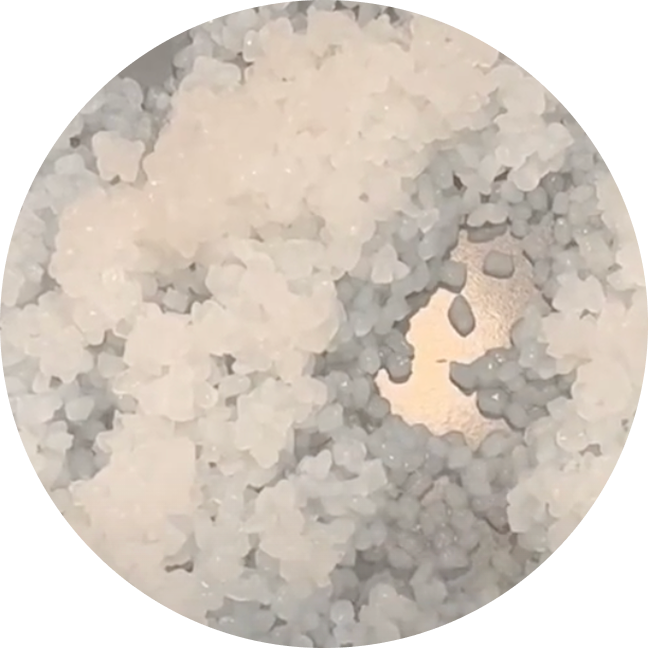 Close-up of coarse white grains on a reflective surface.