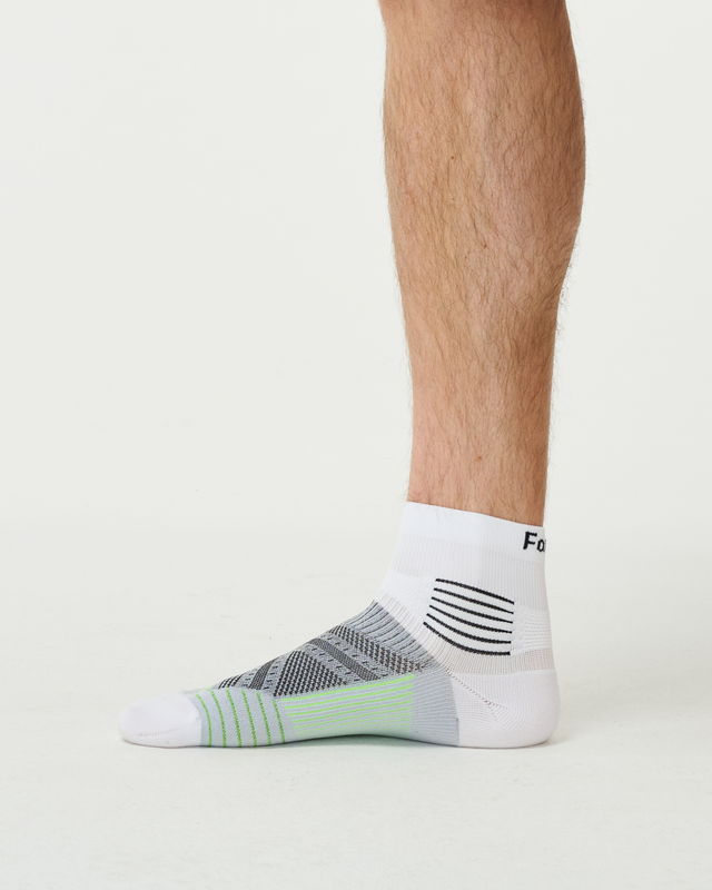 A side view of a person's lower leg and foot wearing a white, grey, and neon green athletic sock.