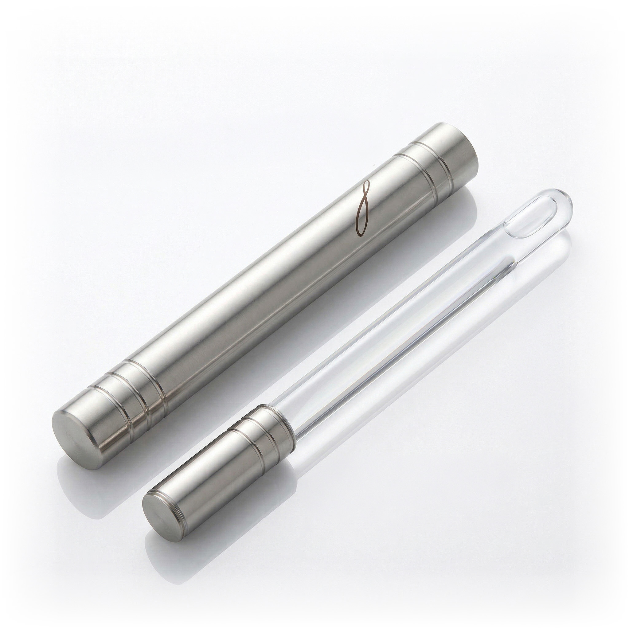 A brushed metal tube case lies next to a clear glass wand applicator on a white background.