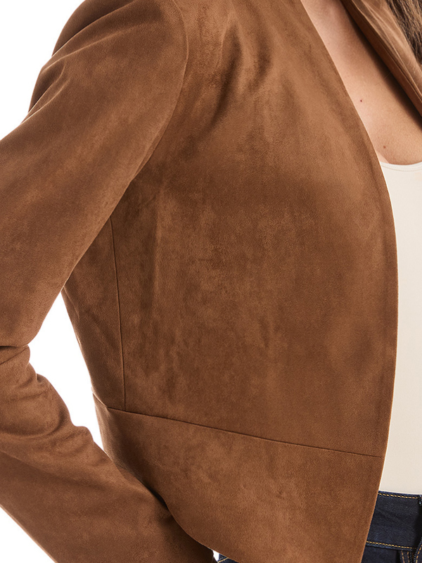 Close-up of a brown suede jacket worn over a white top.