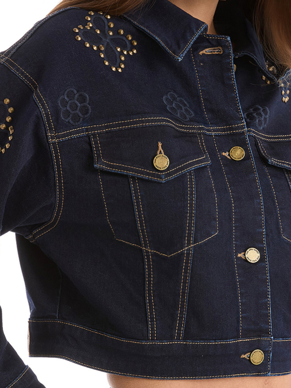 Close-up of a denim jacket with gold buttons and floral embroidery.