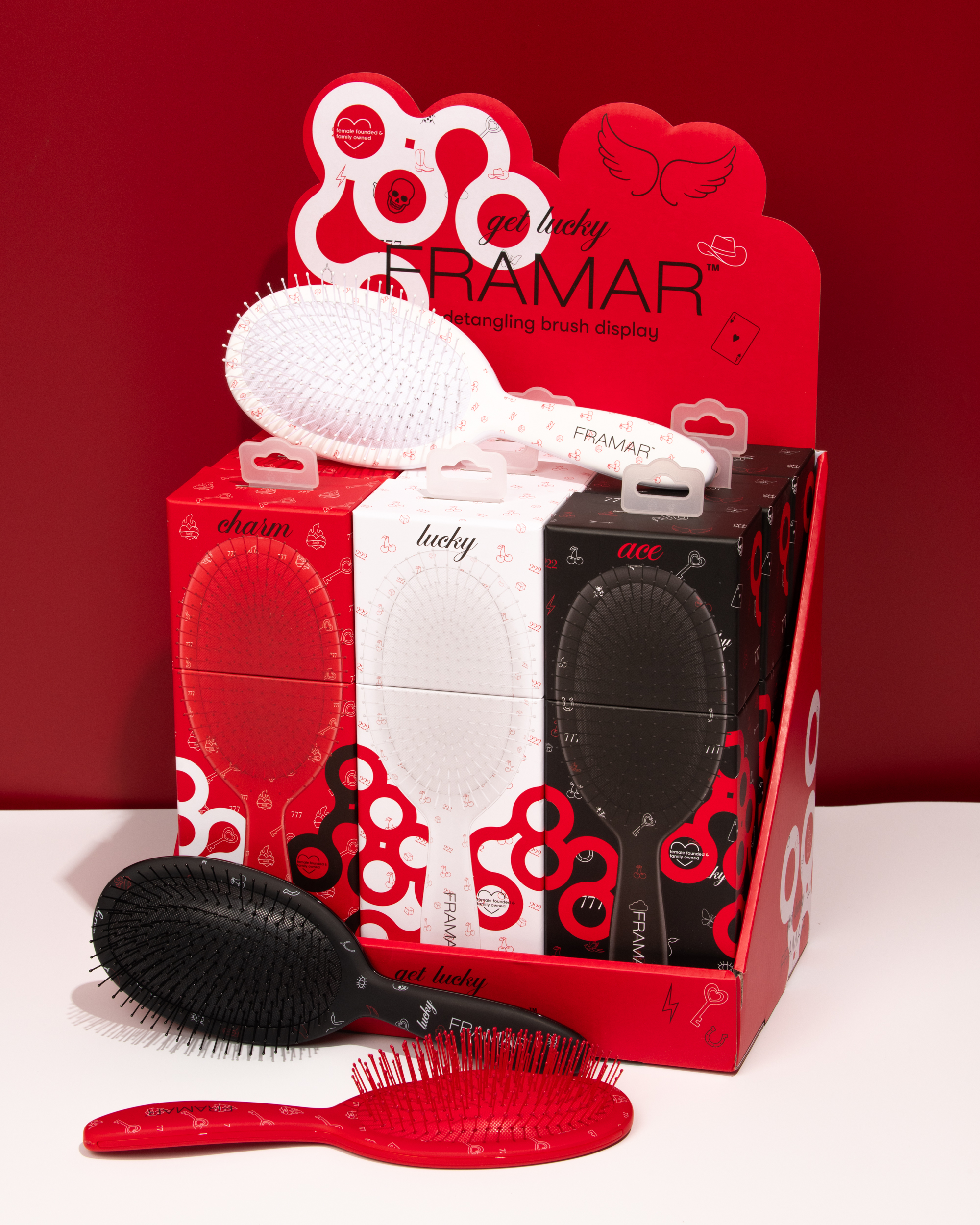 Display of Framar detangling brushes in red, white, and black packaging.