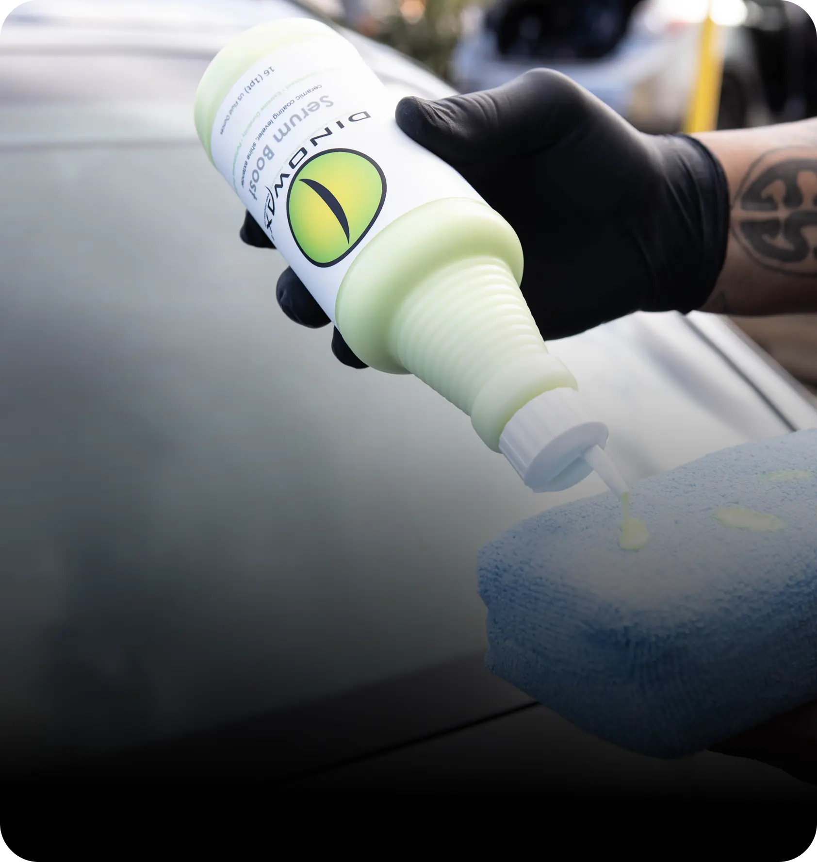 Gloved hand applying liquid from a bottle onto a blue sponge.