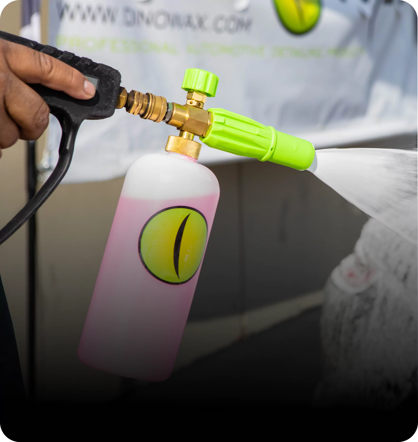 Person using a spray gun with a pink liquid bottle attached.