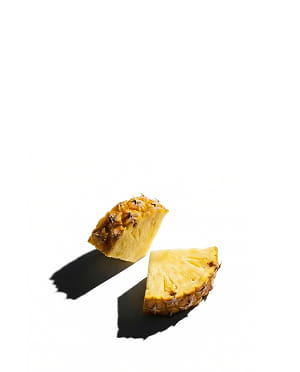 Two wedges of fresh pineapple with harsh shadows on a stark white background.