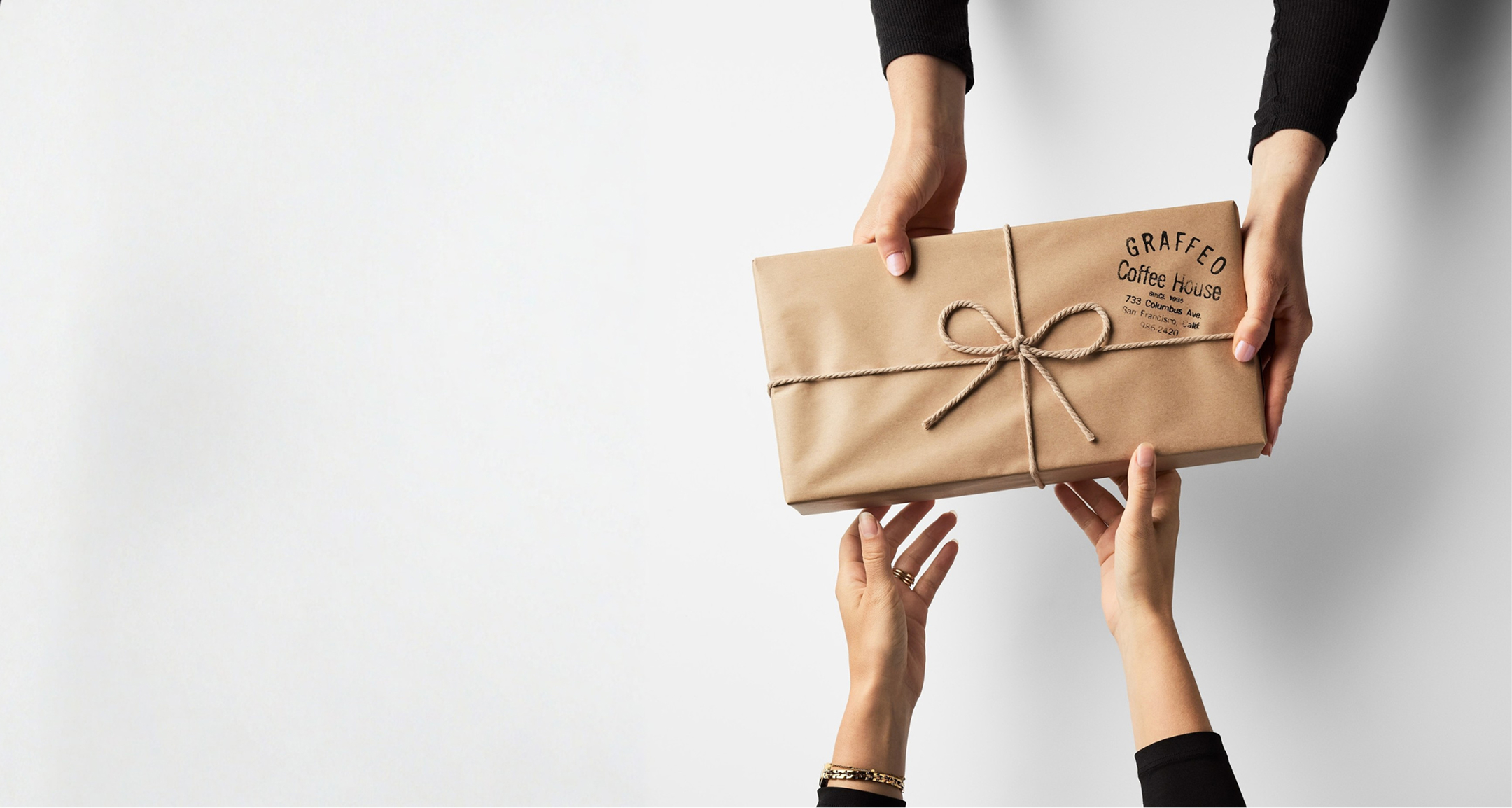 A person hands a package from Graffeo Coffee House to another against a white background.