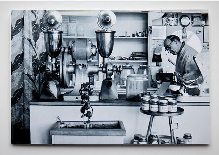 Black and white photo of a man working in a laboratory with equipment and jars.