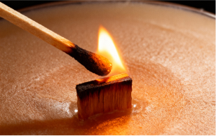 A match lighting a wooden wick in a candle.