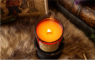 A lit candle on a furry surface, surrounded by books and decorative items.