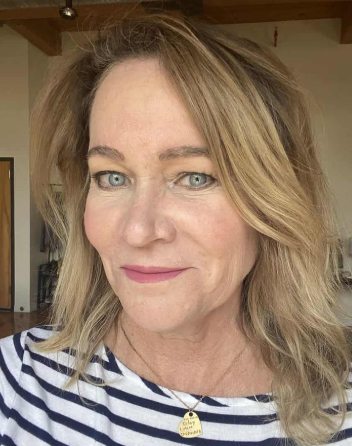 A close-up photo of a smiling woman with blonde hair and blue eyes wearing a striped shirt.