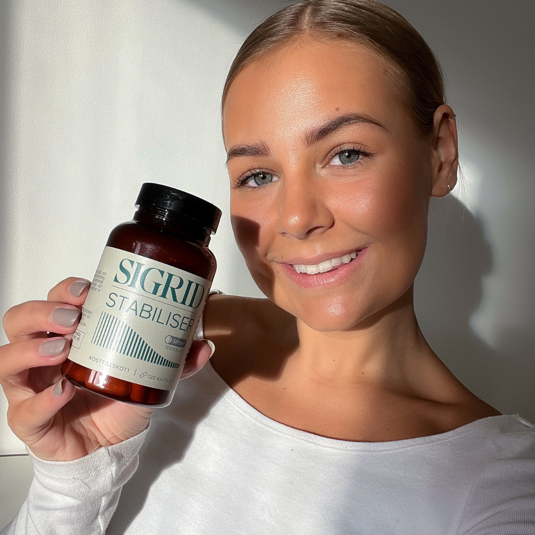 Person holding a bottle labeled 'Sigrid Stabiliser' and smiling.