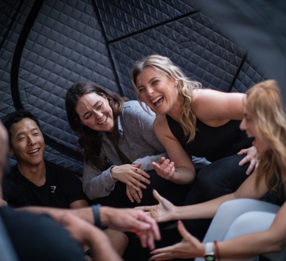 Group of people laughing and sitting inside a quilted tent.