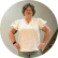 A blurry, circular photo of a woman with short dark hair and glasses smiling with her hands on her hips.